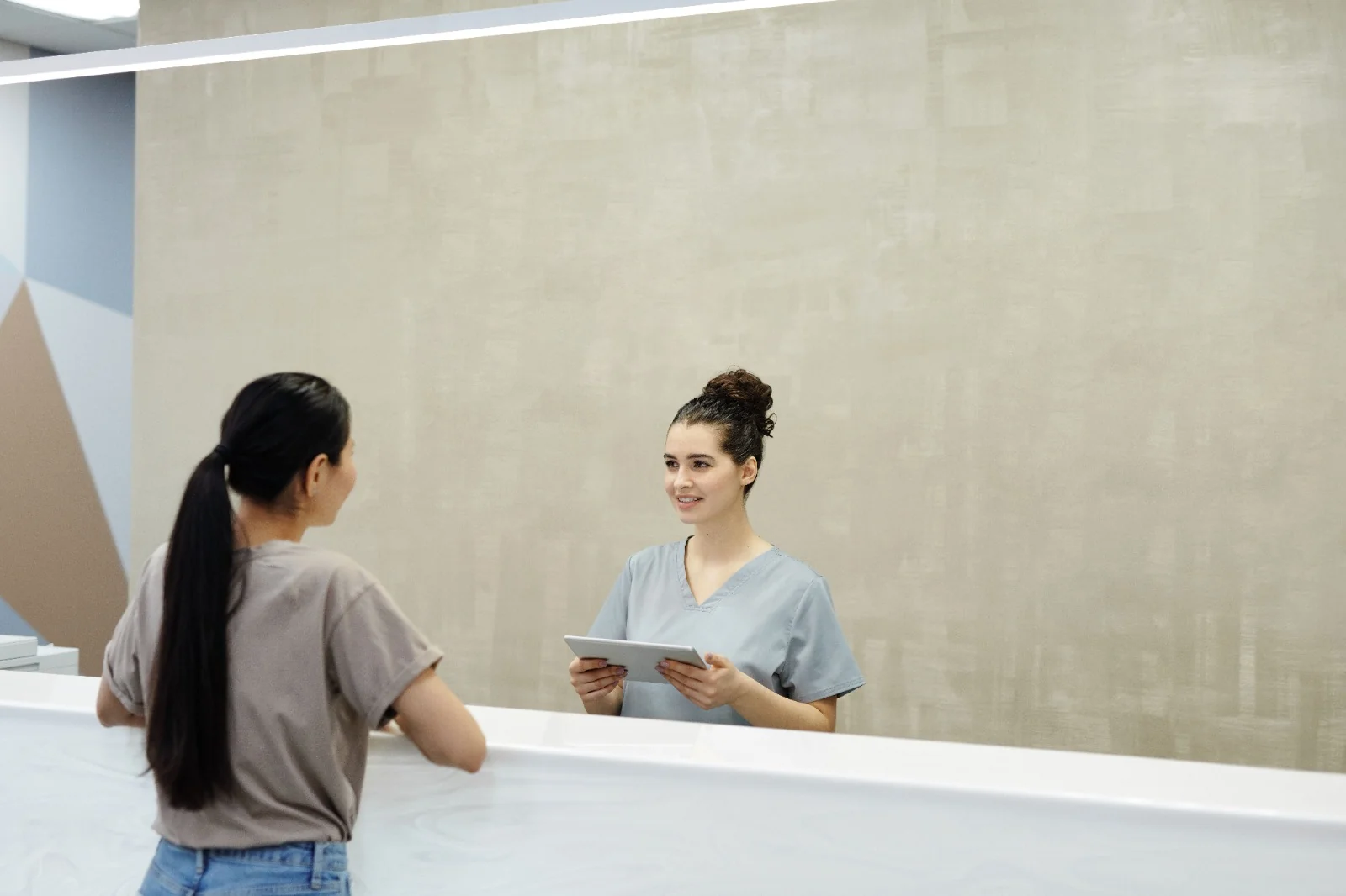 Private clinic professional welcoming a patient at a modern clinic reception desk